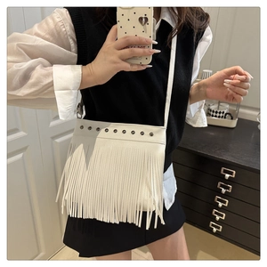 Detalle del bolso bohemio blanco con flecos, tachuelas de metal y borlas alargadas