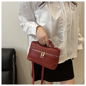 Detail of red woven leather mini vanity bag featuring gold hardware and adjustable strap