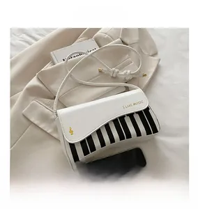 Detailed close-up of piano key motif on white leather handbag with golden music lettering