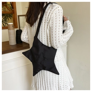 Detail of black star-shaped crossbody nylon bag worn with a white summer dress