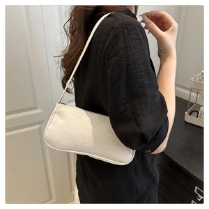 Détail du sac à bandoulière blanc à motif crocodile sur un mannequin au style épuré