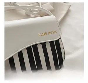 Detail of piano key print handbag featuring I LIKE MUSIC gold embroidery and fine stitching