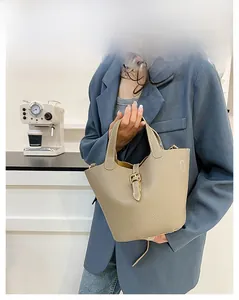 Close-up of litchi grain leather texture and metal buckle on khaki bucket bag