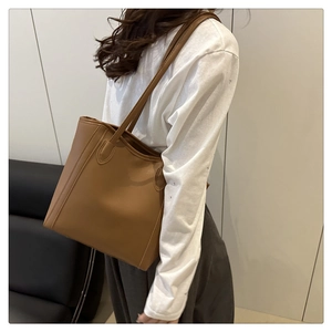 Detailed side view of a minimalist brown leather tote bag worn over the shoulder