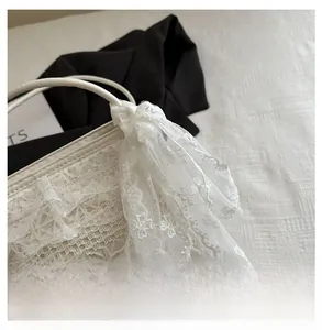 Gros plan d'un sac bandoulière blanc orné de dentelle délicate et d'un grand nœud élégant