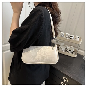 Détail du sac baguette blanc motif crocodile avec finitions argentées sur un mannequin