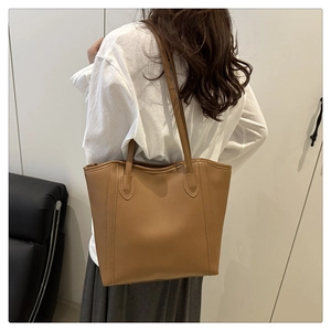 Detailed back view of a caramel leather tote bag worn as a spacious shoulder bag
