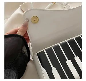 Detail showing the magnetic gold clasp and black-white piano key pattern on a PU bag