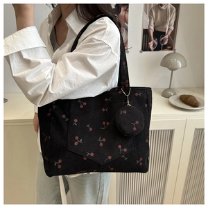 Detail of black corduroy tote bag featuring red cherry patterns and a round coin purse