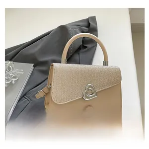 Detail of champagne gold sequin flap with silver heart-shaped metal buckle on beige bag