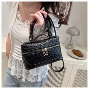 Detail of black woven leather mini handbag with gold zippers and slim crossbody strap