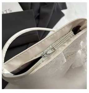 Détail de la fermeture éclair argentée sur le sac en dentelle beige et doublure cuir