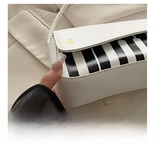 Close-up of precise stitching on white piano key handbag with gold logo detail