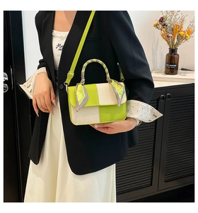 Detail of crossbody bag with silk scarf handle on model in indoor setting