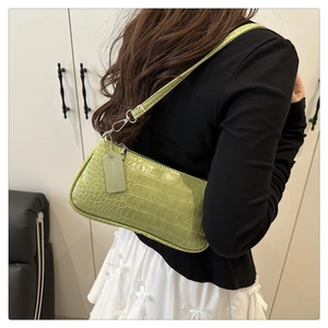 Détail d'un sac baguette vert brillant à motif crocodile avec zip argenté élégant