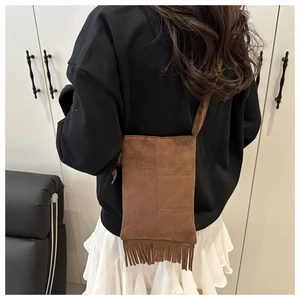 Brown faux suede crossbody bag with fringe detail worn by model in casual style
