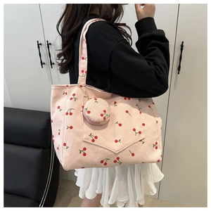 Détails d'un sac cabas en velours côtelé rose avec imprimé cerises porté épaule