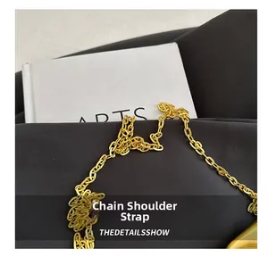Close-up of golden metal chain shoulder strap on a black knit fabric background