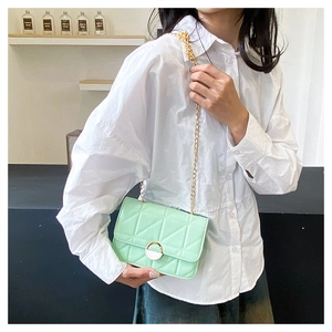 Detail of mint green quilted crossbody bag featuring gold chain and circular lock