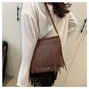 Brown leather tassel bucket bag with silver studs worn by a model in a back view pose