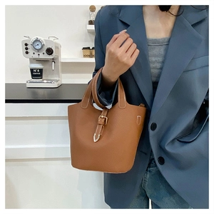 Detail of lychee pattern leather bucket bag with contrast stitching and metal buckle