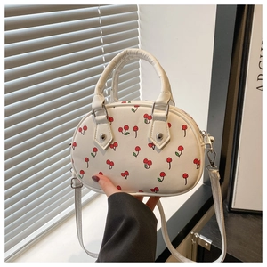 Close-up of white PU leather handbag with red cherry print and silver hardware details