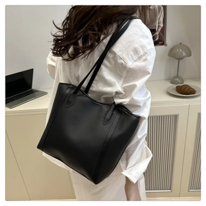 Detail of minimalist black tote bag with long straps shown in a modern lifestyle setting