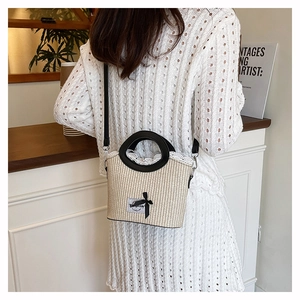 Détail du sac seau en paille avec poignée en cuir noir et décor de doublure en dentelle