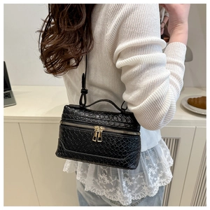 Close-up of woven texture and gold double zippers on the black crossbody box bag