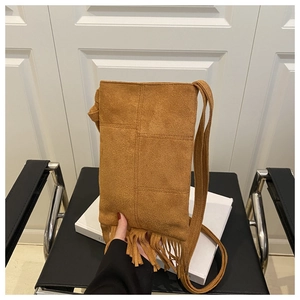 Detail of brown suede crossbody bag featuring long bohemian tassels and vintage texture