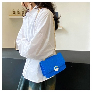 Detail of blue quilted crossbody bag featuring gold chain strap and metal buckle