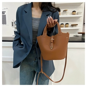 Detail of caramel lychee grain leather tote with metal buckle and shoulder strap