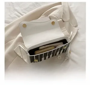 Detail showing internal capacity of the piano pattern shoulder bag with a phone and wallet