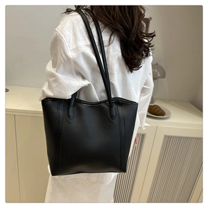 Back view of minimalist black tote bag worn on shoulder, showing high-capacity design