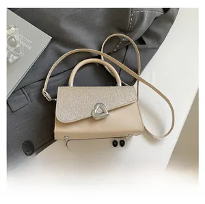 Detail of beige handbag with sequined flap, heart lock, and phone for size reference