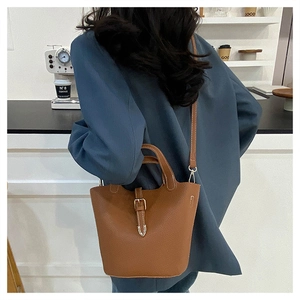 Detailed view of brown lychee grain leather bucket bag with metallic belt buckle closure