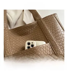 Detail of coffee brown woven tote bag featuring a side pocket with a smartphone inside