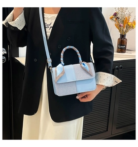 Light blue crossbody bag with silk scarf handle detail and textured paneling