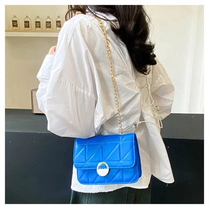Blue crossbody bag with diamond quilting and gold chain strap shown on model shoulder