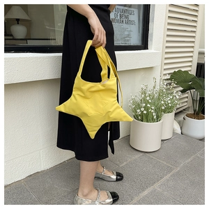 Street style shot of a trendy yellow star-shaped canvas tote bag held by a model