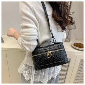 Detail of black woven texture leather handbag with gold double zippers and top handle