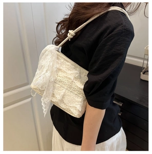 Détail du sac bandoulière en dentelle blanche avec nœud élégant et bandoulière nouée