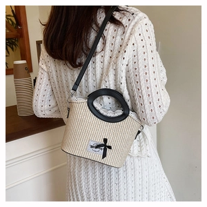 Détail du sac seau en paille avec dentelle, poignée anneau noire et décoration ruban
