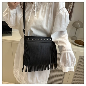 Detail of black pebbled leather bucket bag with silver studs and long fringe tassels