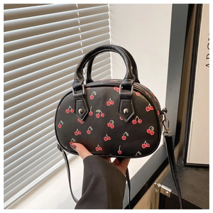 Detail of cherry print handbag showing textured faux leather and durable rolled handles