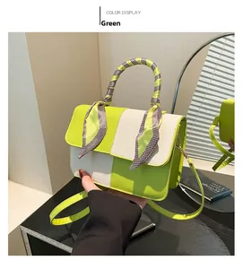 Detail of green and white color-block crossbody bag with silk scarf wrapped handle
