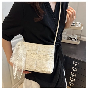 Détail du sac cabas en dentelle crème avec volants superposés et ruban décoratif