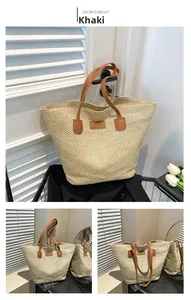 Close-up of khaki straw tote bag with brown leather handles and fashion label detail