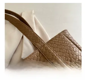 Detailed close-up of the woven leather texture and seam on a brown tote handbag