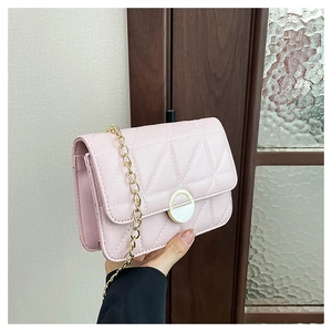 Detail of pink quilted crossbody bag with golden chain strap and round metal buckle